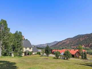 Nestled amidst rolling hills and majestic mountains, this expansive property offers a serene retreat with multiple structures.