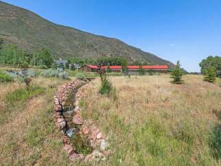 Discover this stunning property featuring a charming stream with rock accents winding through lush, natural landscaping.