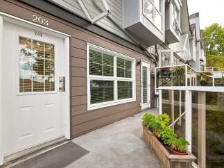 Discover this charming townhouse featuring a welcoming entrance with a white door and a prominent address number '203'.