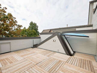 Enjoy the outdoors on this spacious rooftop deck, featuring a unique sloped skylight and a modern wooden plank flooring.