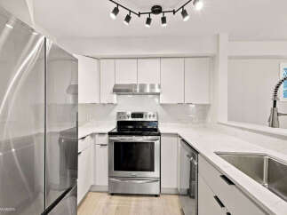 Experience modern living in this sleek kitchen, featuring stainless steel appliances and pristine white cabinetry.