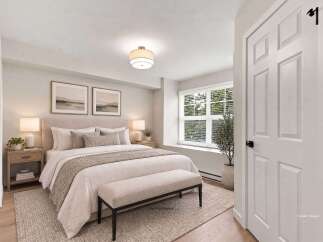 Step into this serene bedroom, featuring a plush king-sized bed adorned with soft linens and decorative pillows.
