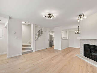 Step into this beautifully renovated living space featuring a modern fireplace and elegant hardwood floors.