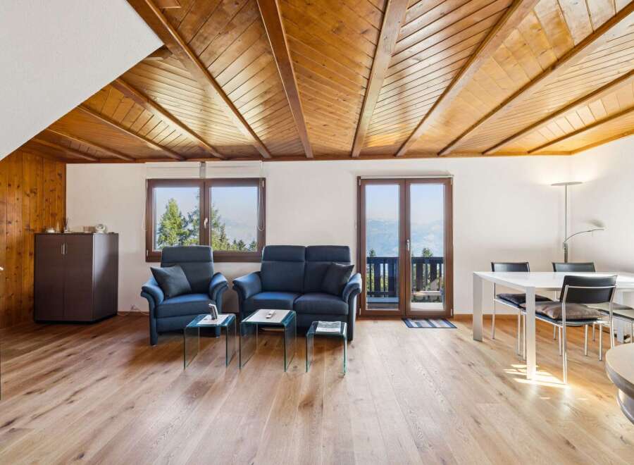Experience breathtaking mountain views from this charming living and dining area, featuring a cozy seating arrangement with two plush armchairs and a sofa, complemented by elegant glass coffee tables.