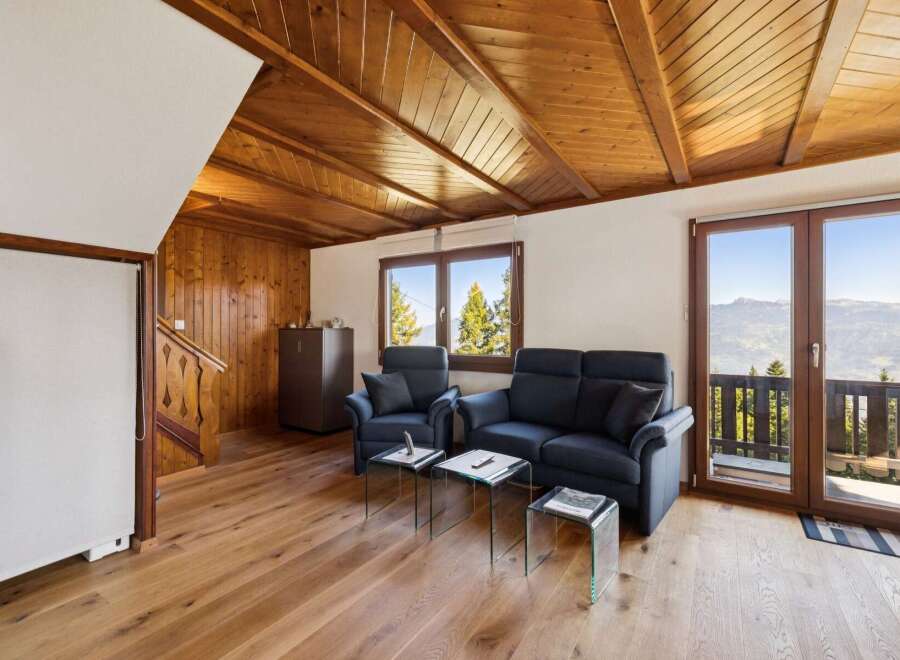 Experience breathtaking mountain views from this charming living room, featuring a cozy seating area with a sofa and armchairs, perfect for relaxing after a day of adventure.