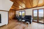 Experience breathtaking mountain views from this charming living room, featuring a cozy seating area with a sofa and armchairs, perfect for relaxing after a day of adventure.