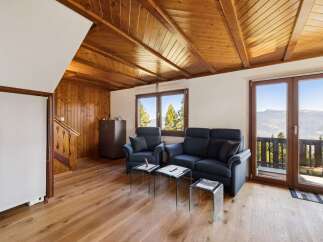 Experience breathtaking mountain views from this charming living room, featuring a cozy seating area with a sofa and armchairs, perfect for relaxing after a day of adventure.