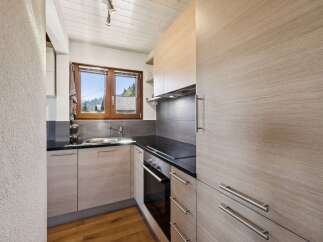 Discover this charming kitchen featuring modern light wood cabinetry and sleek black countertops.