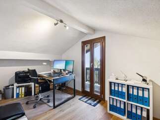 This attic home office features a spacious desk with dual monitors, a comfortable ergonomic chair, and ample storage with a printer and filing cabinets.