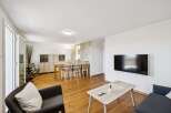 Experience modern living in this spacious open-plan apartment, featuring a combined living and dining area with elegant wooden floors and a stone accent wall.