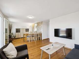 Experience modern living in this spacious open-plan apartment, featuring a combined living and dining area with elegant wooden floors and a stone accent wall.