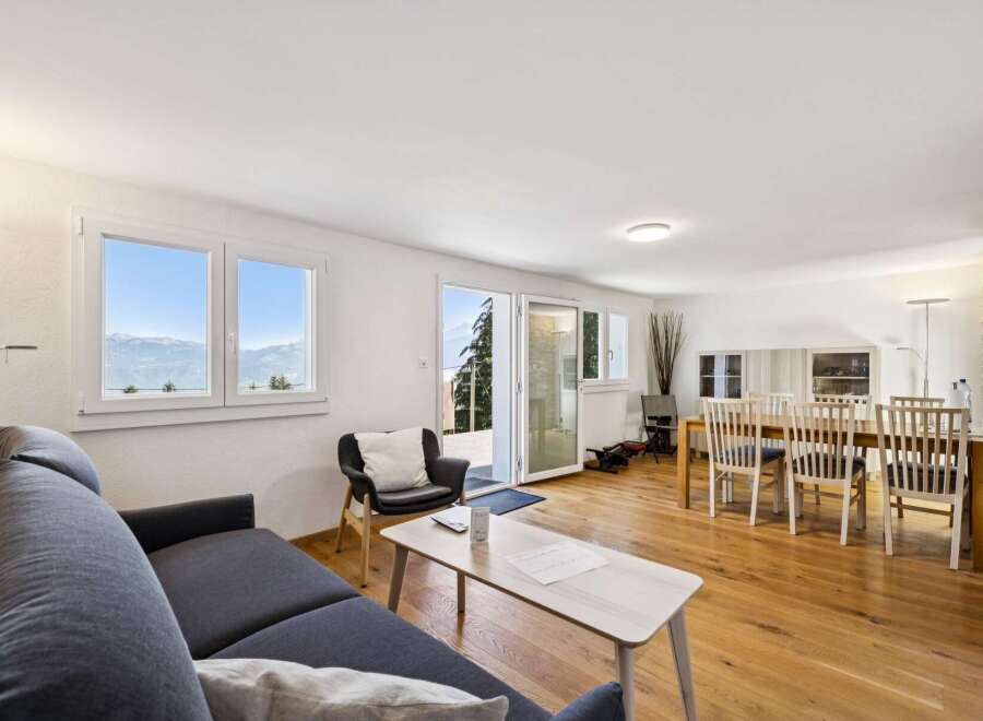 Experience breathtaking mountain views from this stunning living and dining area, featuring a comfortable sectional sofa and a spacious dining table perfect for entertaining.