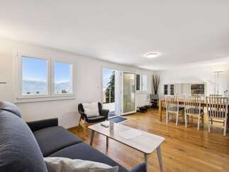 Experience breathtaking mountain views from this stunning living and dining area, featuring a comfortable sectional sofa and a spacious dining table perfect for entertaining.
