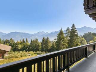 Experience breathtaking mountain views from this charming property, nestled amidst lush greenery and towering pine trees.