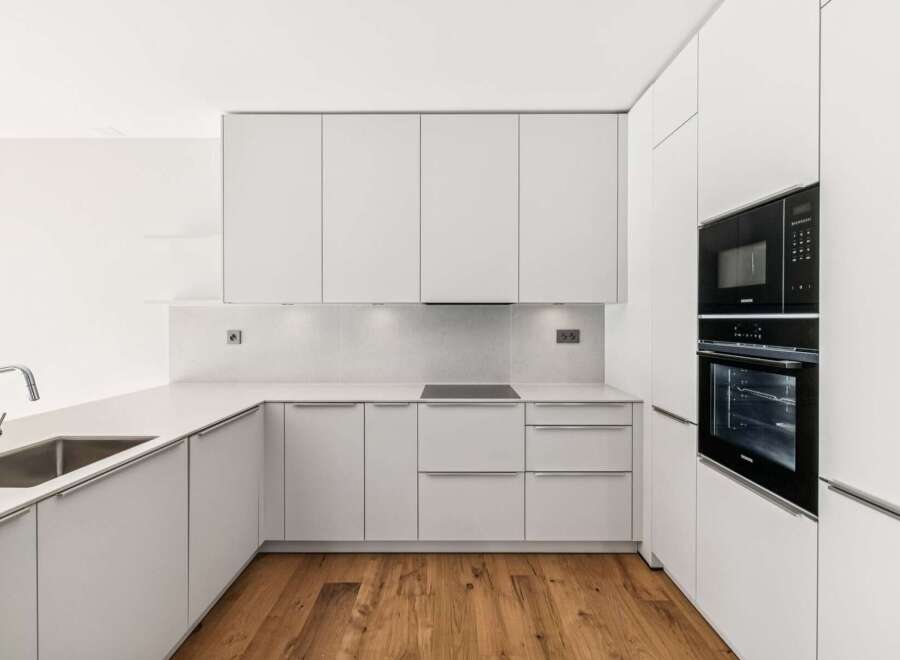 Experience modern living in this sleek, minimalist kitchen featuring clean white cabinetry and integrated appliances.