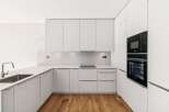 Experience modern living in this sleek, minimalist kitchen featuring clean white cabinetry and integrated appliances.