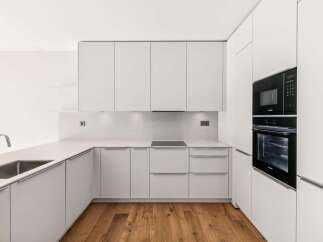 Experience modern living in this sleek, minimalist kitchen featuring clean white cabinetry and integrated appliances.