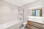 Experience modern comfort in this beautifully appointed bathroom, featuring a sleek bathtub with a glass shower screen and a wall-mounted toilet.
