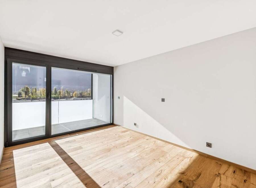 Experience modern living in this bright and airy room featuring a spacious balcony accessible through large sliding glass doors.