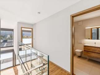 Experience modern living in this stunning home featuring a sleek glass-railed staircase and expansive windows that flood the space with natural light.