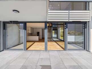 Experience modern living with this stunning property featuring expansive sliding glass doors that open onto a spacious patio.