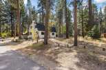 Nestled among tall pine trees, this charming white A-frame home offers a serene mountain retreat.