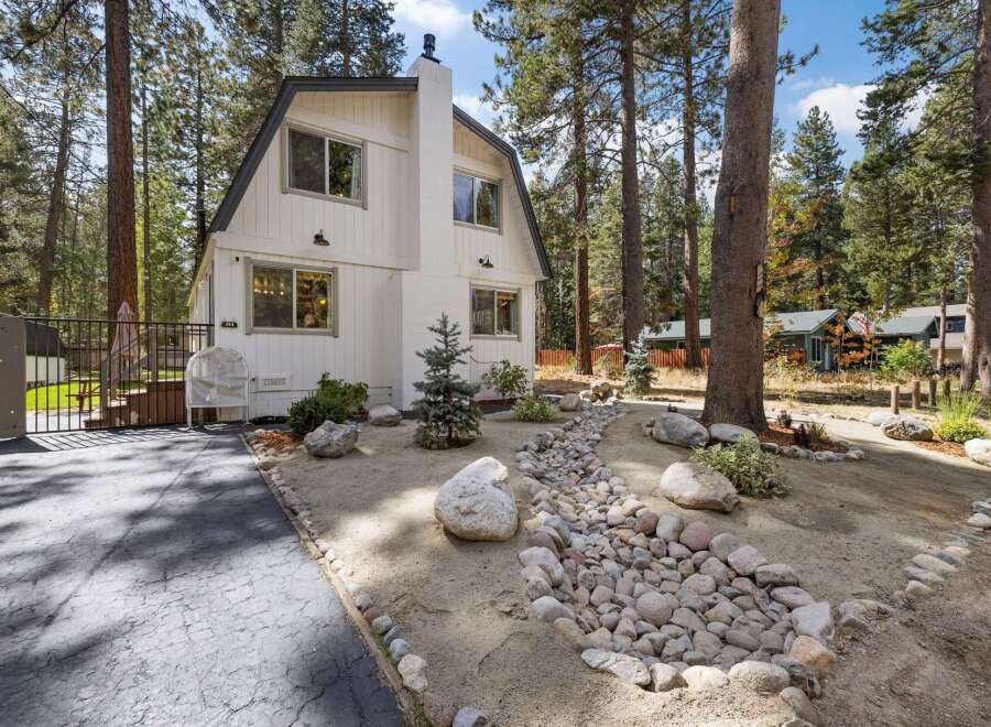 Nestled amongst tall pine trees, this charming white home offers a serene retreat.