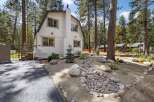 Nestled amongst tall pine trees, this charming white home offers a serene retreat.
