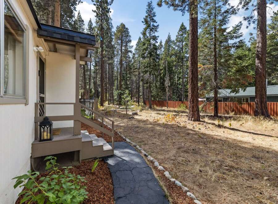 Discover this charming home nestled amongst tall pine trees, offering a serene and private setting.