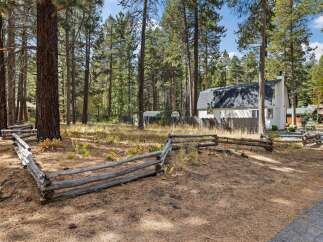 Nestled amidst tall pine trees, this charming property offers a serene retreat with a rustic split-rail fence bordering the grounds.