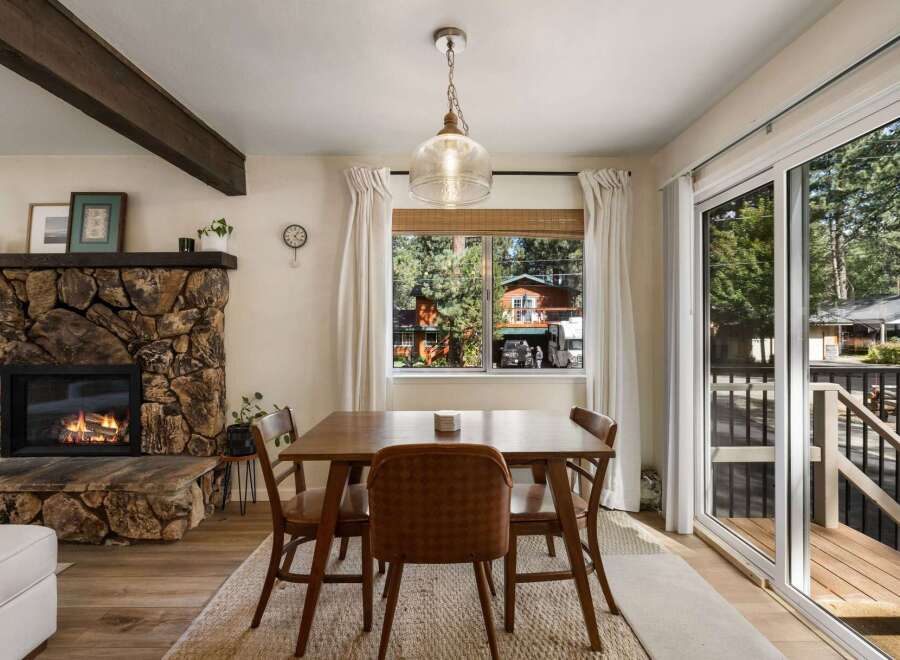 Cozy dining area featuring a rustic stone fireplace and a warm wooden dining set.