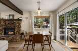 Cozy dining area featuring a rustic stone fireplace and a warm wooden dining set.