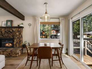 Cozy dining area featuring a rustic stone fireplace and a warm wooden dining set.