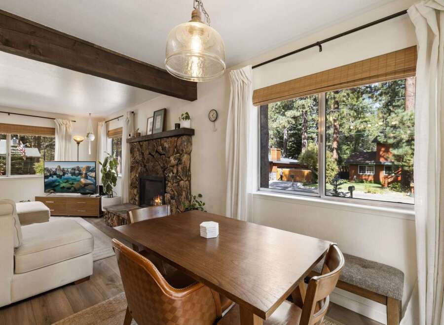 Cozy living room featuring a stone fireplace and a large window with scenic forest views.
