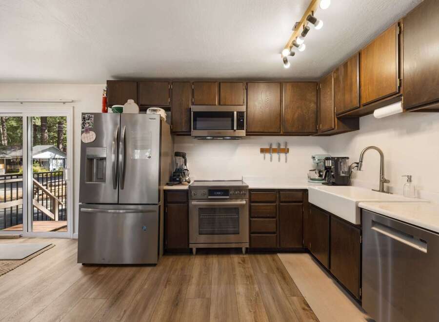 This spacious kitchen boasts dark wood cabinetry, a sleek stainless steel refrigerator, and a modern microwave.