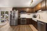 This spacious kitchen boasts dark wood cabinetry, a sleek stainless steel refrigerator, and a modern microwave.