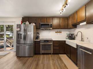 This spacious kitchen boasts dark wood cabinetry, a sleek stainless steel refrigerator, and a modern microwave.