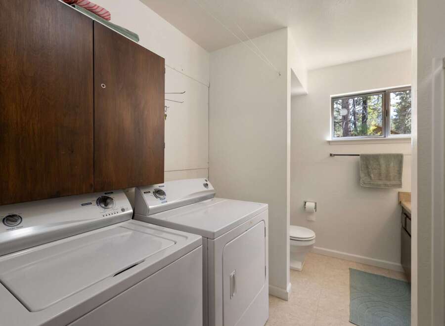 This laundry room offers ample storage with a large wooden cabinet above the washer and dryer.