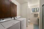 This laundry room offers ample storage with a large wooden cabinet above the washer and dryer.