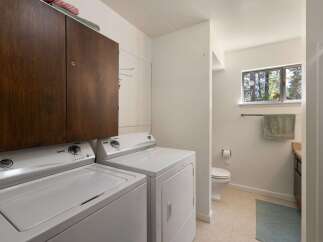 This laundry room offers ample storage with a large wooden cabinet above the washer and dryer.