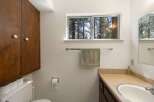 This bathroom features a large wooden cabinet for ample storage, a toilet with extra rolls of toilet paper, and a wall-mounted toilet paper dispenser.