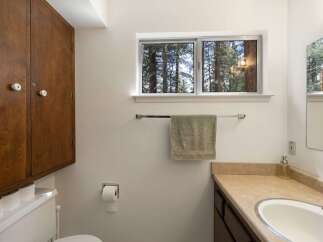 This bathroom features a large wooden cabinet for ample storage, a toilet with extra rolls of toilet paper, and a wall-mounted toilet paper dispenser.