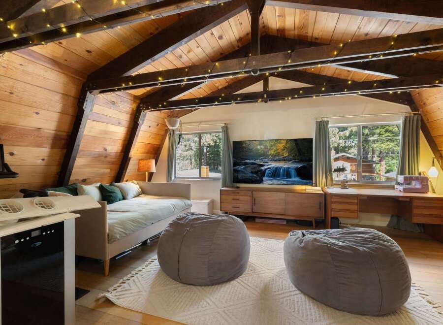 Experience cozy living in this charming attic room, featuring a comfortable daybed, plush beanbag chairs, and a large flat-screen TV for entertainment.