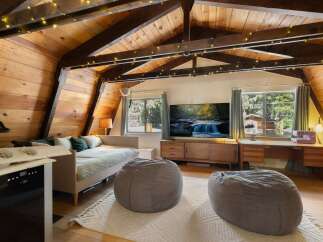 Experience cozy living in this charming attic room, featuring a comfortable daybed, plush beanbag chairs, and a large flat-screen TV for entertainment.
