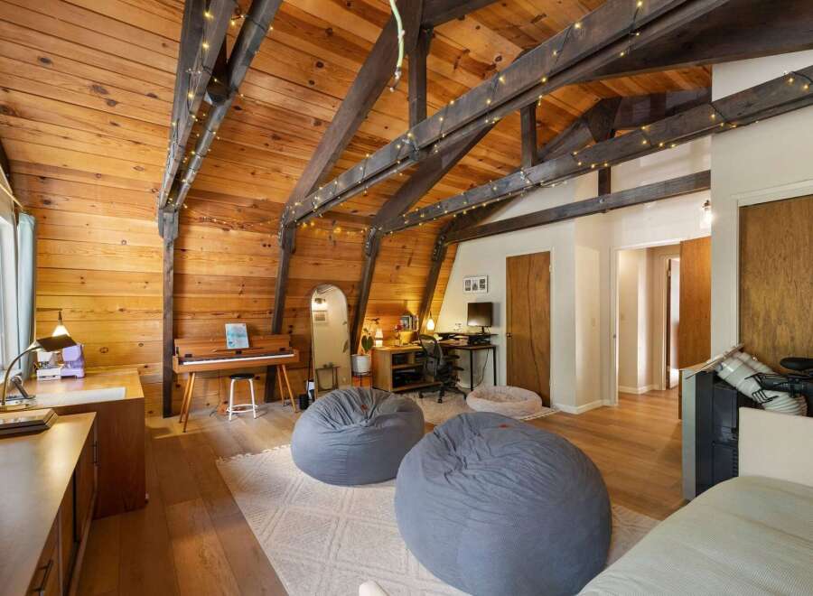 This charming attic room features a warm wooden interior with exposed beams and decorative string lights, creating a cozy ambiance.