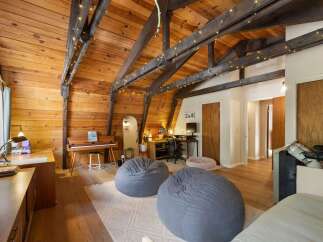 This charming attic room features a warm wooden interior with exposed beams and decorative string lights, creating a cozy ambiance.