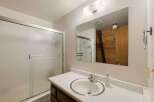 This bathroom features a frosted glass sliding shower door, a white basin sink with a chrome faucet, and a large vanity mirror.