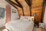 Experience cozy mountain living in this charming bedroom featuring a vaulted wood-paneled ceiling with exposed beams.