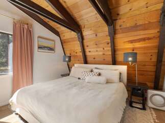 Experience cozy mountain living in this charming bedroom featuring a vaulted wood-paneled ceiling with exposed beams.