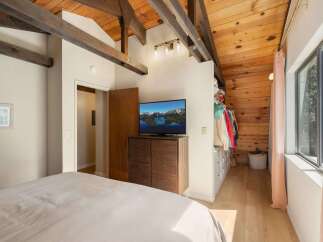 Experience rustic charm in this bedroom featuring exposed wooden beams and a vaulted ceiling.